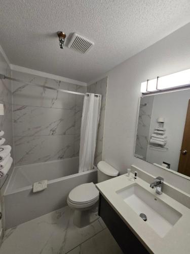 a white bathroom with a toilet and a sink at Super 8 by Wyndham Salmon Arm in Salmon Arm