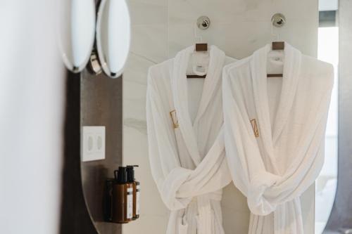 a white robe hanging on a rack in a bathroom at MiFlow Hotel Villas & Suites in Miami Platja