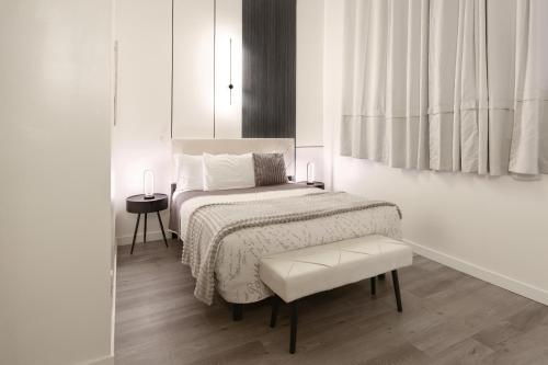 a white bedroom with a bed and a chair at Hotel Auberge Manoir Ville Marie in Montréal