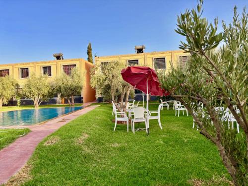 a group of tables and chairs with a red umbrella at Complexe Kariat Ayoub in Aït Zat