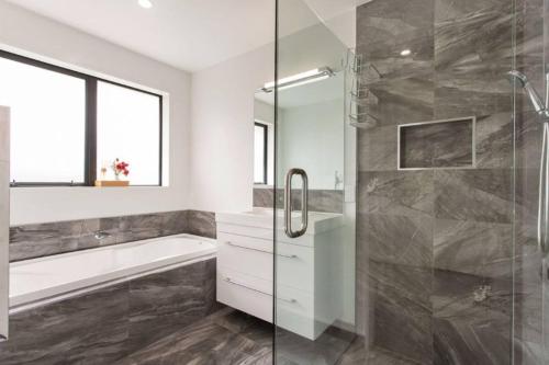 a bathroom with a shower and a tub and a sink at Family-Friendly Home in Wigram with Style & Space in Christchurch