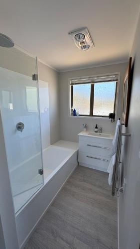 a bathroom with a shower and a tub and a sink at 4 Bedroom Family Beach House in Hauturu