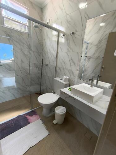a bathroom with a toilet and a sink and a shower at Canto Sul Suítes in Ubatuba