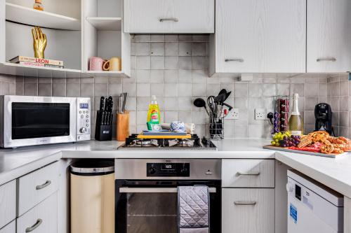 a kitchen with a stove and a microwave at Tattenhoe House with Free Parking, Fast Wifi, Garden and Smart TV by Yoko Property in Milton Keynes