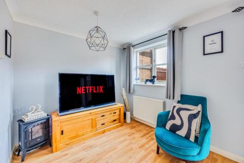 a living room with a tv and a blue chair at Tattenhoe House with Free Parking, Fast Wifi, Garden and Smart TV by Yoko Property in Milton Keynes