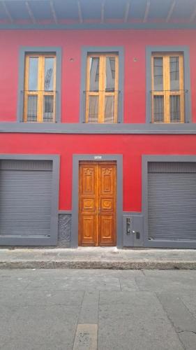 a red building with two garages and a wooden door at Apartaestudio comodo y central S2 - WiFi in Pasto