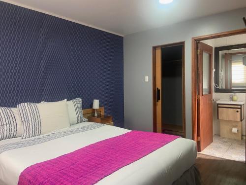 um quarto com uma cama grande e um cobertor rosa em Cabañas Bosque Austral em Punta Arenas
