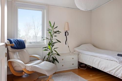 a bedroom with a chair and a plant next to a bed at Spectacular Villa - Pool, Sauna & Magical Lake View in Lidingö