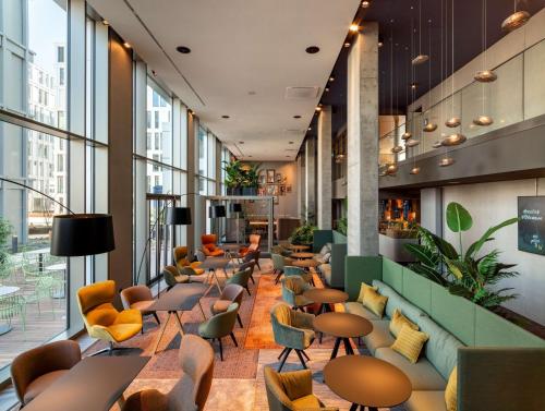 a lobby with chairs and tables and windows at b'mine Hotel Frankfurt Airport in Frankfurt/Main