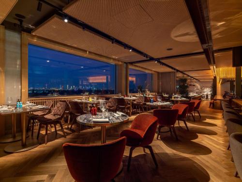 a restaurant with tables and chairs and a view of the city at b'mine Hotel Frankfurt Airport in Frankfurt/Main