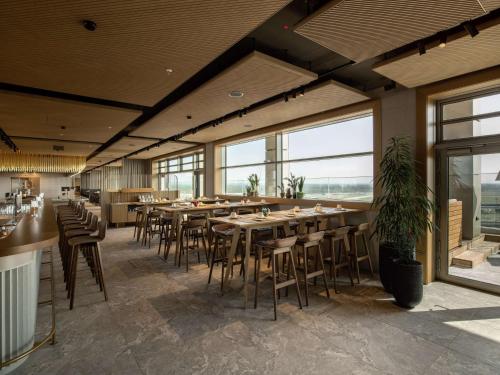a restaurant with tables and chairs and large windows at b'mine Hotel Frankfurt Airport in Frankfurt/Main