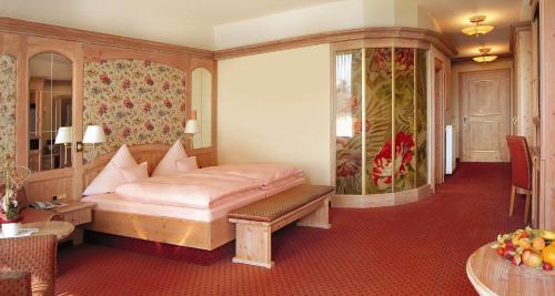 a bedroom with a bed and a bench in a room at Wellness-& Nationapark Hotel Schliffkopf, BWSC in Baiersbronn