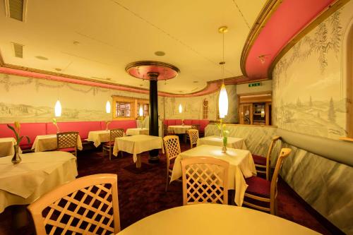 a restaurant with white tables and chairs in a room at Wellness-& Nationapark Hotel Schliffkopf, BWSC in Baiersbronn