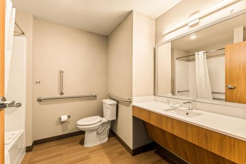 a bathroom with a toilet and a sink and a mirror at LivAway Suites Salt Lake City- West Jordan in West Jordan