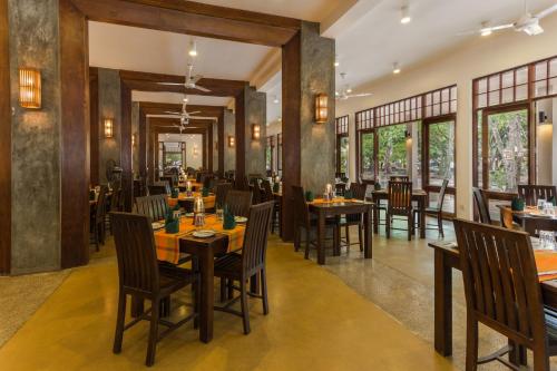 a restaurant with wooden tables and chairs and windows at Nilaveli Beach Hotel in Nilaveli