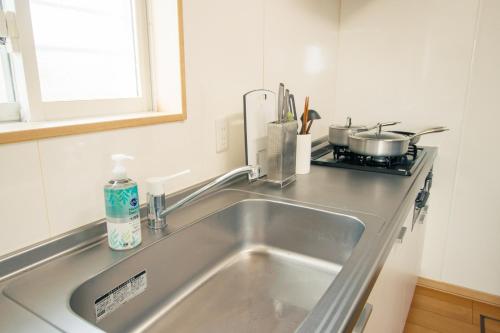 a kitchen with a sink and a stove at Lapacho 子どもが絶対満足する宿 民泊らぱちょ in Kumamoto