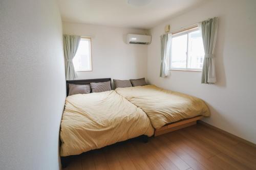 a bed in a bedroom with two windows at Lapacho 子どもが絶対満足する宿 民泊らぱちょ in Kumamoto