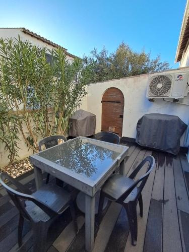 une table et des chaises sur une terrasse en bois dans l'établissement Appartement cosy entièrement climatisé, à Saintes-Maries-de-la-Mer
