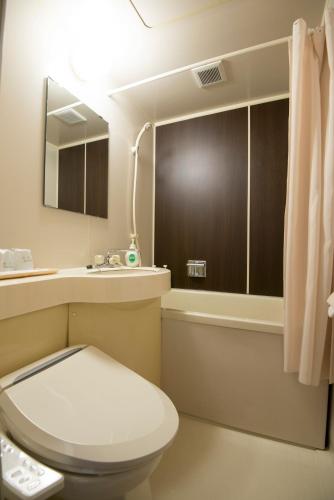 a bathroom with a toilet and a sink and a tub at Tenpyo Ryokan in Nara