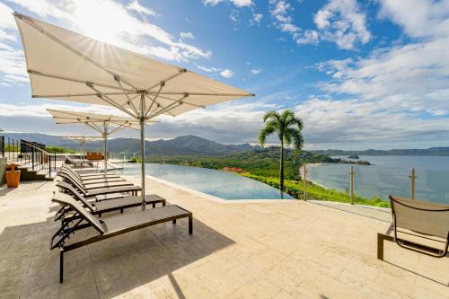 a group of chairs and an umbrella next to a pool at 360 Splendor 105A-Ocean View 2 Br Condo-Breakfast Included! in Playa Flamingo