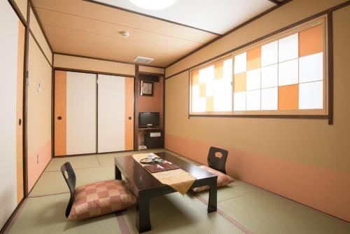 a room with a table and a chair and a window at Tenpyo Ryokan in Nara