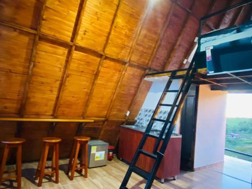 a ladder in a room with wooden ceilings and stools at Cabaña La Victoria in Sasaima
