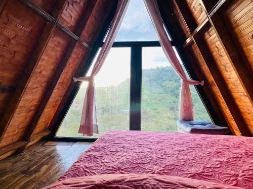 a bed in a room with a large window at Cabaña La Victoria in Sasaima
