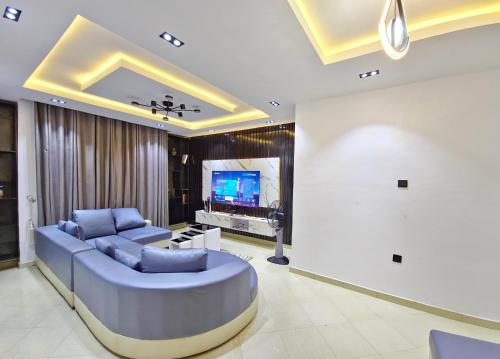 a living room with a large blue couch and a tv at Cozy Ambience 2 in Ibadan