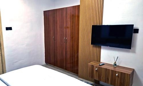 a bedroom with a television and a wooden cabinet at Cozy Ambience 2 in Ibadan