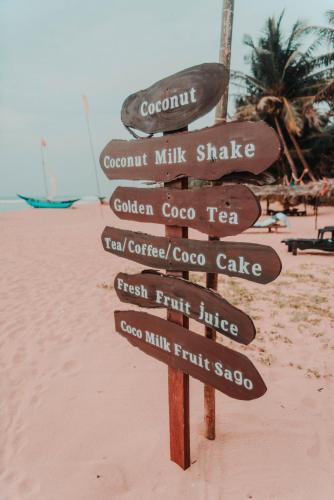a wooden sign on a beach with many signs at Sea Trails Bentota in Bentota