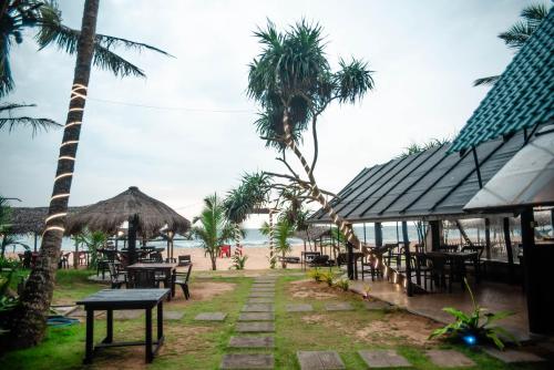 a restaurant on the beach with tables and palm trees at Sea Trails Bentota in Bentota