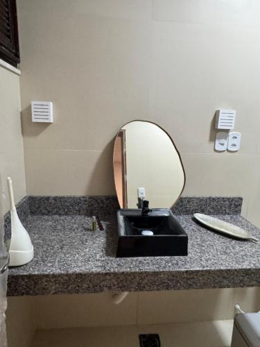 Un mostrador de baño con un lavabo y un espejo. en Suites em mansão, en Fortaleza