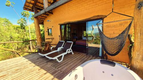 a porch with two chairs and a hammock on a house at Ecopousada Toca do Guará in Alto Paraíso de Goiás