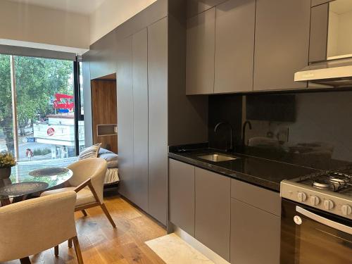 a kitchen with a stove and a table with chairs at Increíbles departamentos en Roma Norte in Mexico City