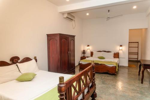 a bedroom with two beds and a dresser at Sea Trails Bentota in Bentota