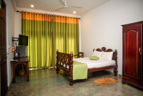 a bedroom with a bed and a green curtain at Sea Trails Bentota in Bentota