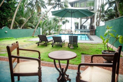 a patio with chairs and a table and an umbrella at Sea Trails Bentota in Bentota