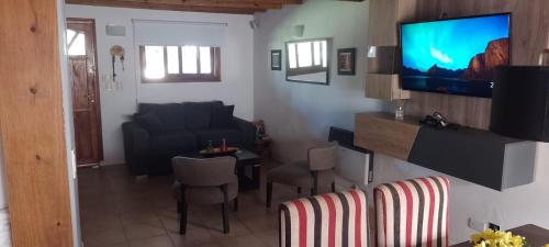 ein Wohnzimmer mit einem Sofa und einem Fernseher an der Wand in der Unterkunft Casa en pinamar in Pinamar