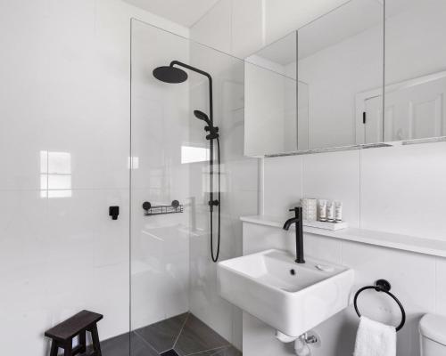 a white bathroom with a sink and a shower at Lavender Cottage - Minutes to Wineries in Cessnock