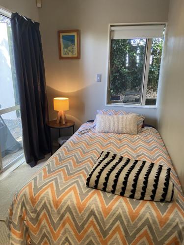 a bedroom with a bed with a lamp and a window at Close Motorway,Free Breakfast,Private & Spacious in Auckland