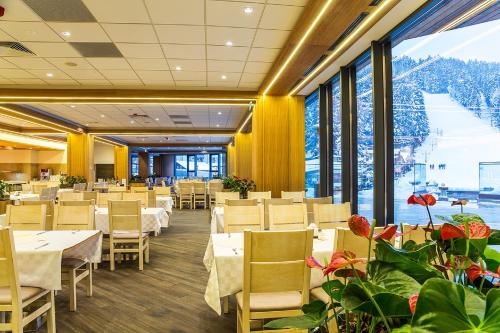 a restaurant with tables and chairs and large windows at Rila Hotel Borovets in Borovets