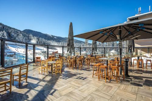 a restaurant with tables and chairs on a deck at Rila Hotel Borovets in Borovets