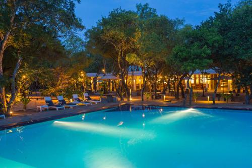a swimming pool at night with chairs and trees at Nilaveli Beach Hotel in Nilaveli
