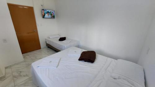 a white room with two beds in a room at Hotel Milagre Das Águas in Aparecida