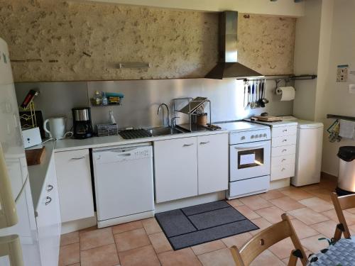 une cuisine avec des armoires blanches et un four à plaques de cuisson dans l'établissement Maison solognote calme et boisée, proche châteaux Loire, golf, vélos, ping-pong - FR-1-590-34, à Jouy-le-Potier