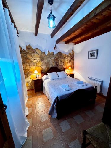 a bedroom with a large bed and a stone wall at Casas Rurales Carrizosa in Navaconcejo