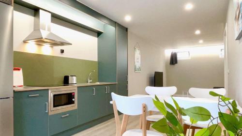a kitchen with a table and some white chairs at The Cliffs - AT Seiramar in Viveiro