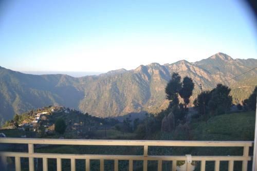 a view of a mountain range with a white fence at Namaha hotel and cottages in Kanatal