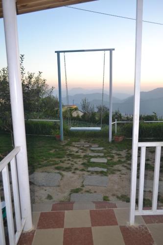 a porch with a swing and a view at Namaha hotel and cottages in Kanatal