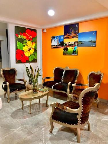a living room with chairs and a table and paintings at Hotel La Herradura in Puerto López